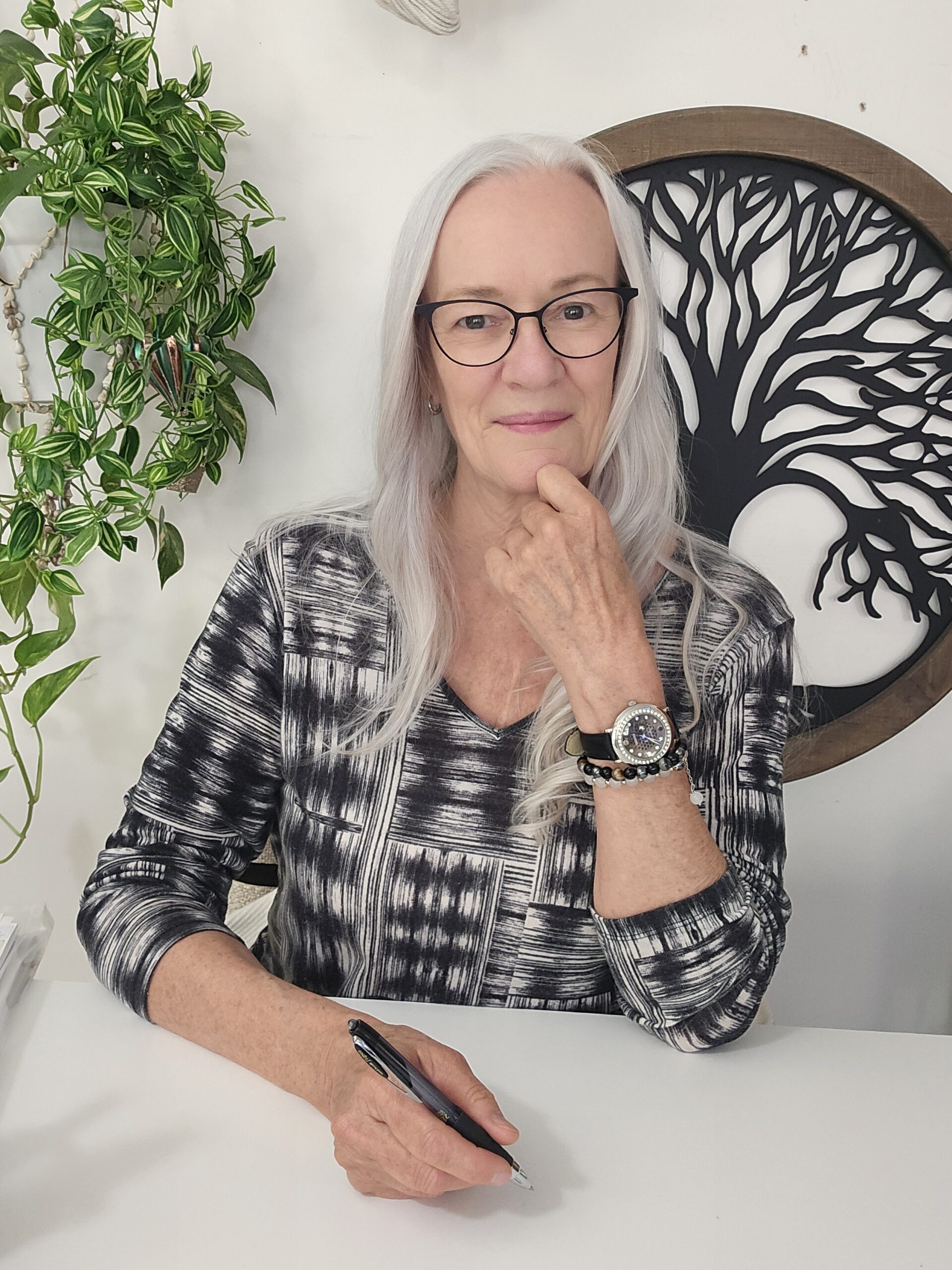 Judy at her desk, thoughtful, pen in hand